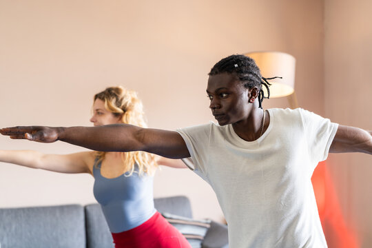 Diverse duo practicing yoga together indoors