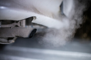 exhaust pipe of a car with exhaust gases on a winter night in the dark