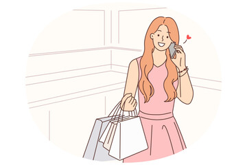Happy woman with shopping bags talking on cell