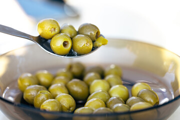 Close-up of Green Olives on a Spoon with Bowl