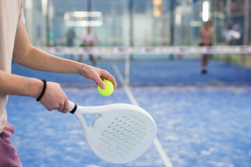 Hands of padel player holding racquet and ball, ready to shot.
