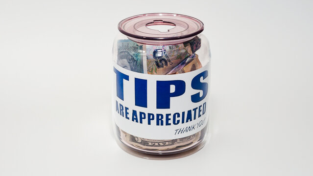 Jarro de propinas con billetes y monedas de varias denominaciones. Propinas de la industria de servicios, salario m&iacute;nimo y concepto de propina como una forma &uacute;nica y creativa de almacenar dinero