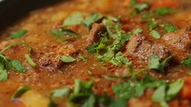 Hungarian goulash soup cooking close-up in pot, chef cook traditional polish or zech soup in restaurant. 