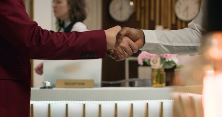Bellboy shaking hands with hotel guest, greeting important businessman at posh hotel. African...