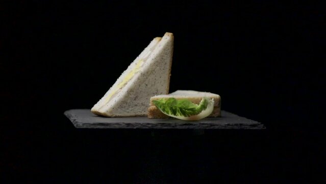 Sandwich at&uacute;n y huevo rotando con fondo negro