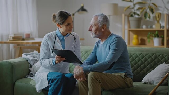 Elderly man listening lady doctor and preparing putting his signature under consent form
