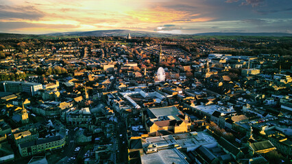 Aerial view of a city Lancaster at sunset with warm lighting, showcasing urban architecture and a distant horizon under a colorful sky.