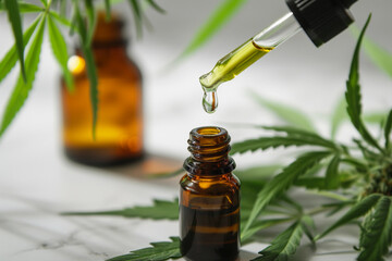 organic CBD oil dropper and bottle, with hemp leaves in the background