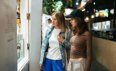 Two girls tourists choosing street food.