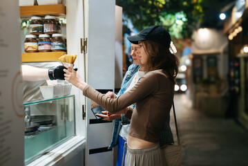 Fototapeta na wymiar Two tourist girls buy street food at a stall.