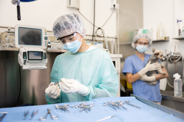 Young guy veterinarian in full protective gear arranges instrument on table desktop, prepares to...