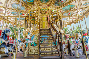Detailed view of a carousel with horses and vehicles.