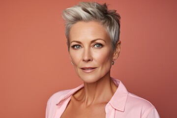 Portrait of a beautiful middle-aged woman with short hair on a pink background