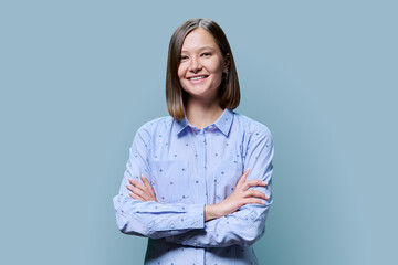 Portrait of confident young woman with crossed arms on blue background