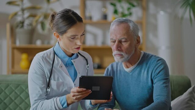 Nurse shows older male patient digital tablet with new software application