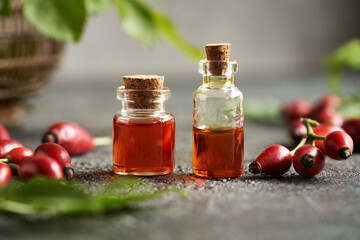 Two bottles of rose hip seed oil with fresh rosehips