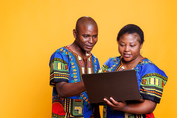 Smiling man and woman using laptop and searching information on internet together. Couple with...