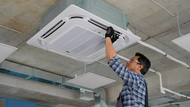 Asian worker sets up air conditioner in office