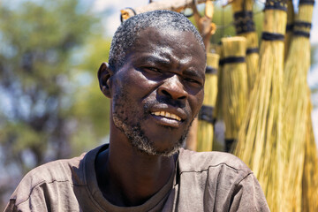 portrait of an handsome middle age african man with masculine features, standing outdoors selling...