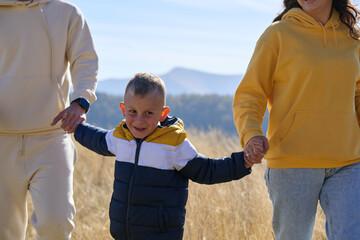 A modern family, along with their son, revels in the joy of a muddy day in nature, running and...