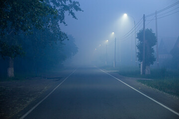 mysterious fog on the street in a small town at night - obrazy, fototapety, plakaty