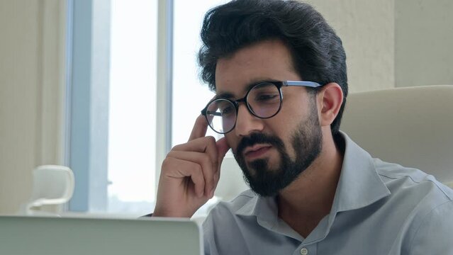 Pensive ethnic man Arabian Indian muslim businessman male employer corporate CEO at office with computer laptop business work planning thinking solve issue think ponder idea problem solution look away