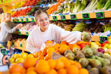 Portrait of teenage girl customer buying sweet oranges at grocery shop