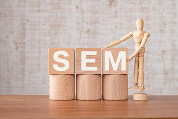 There is wood cube with the word SEM. It is an abbreviation for Search Engine Marketing as...