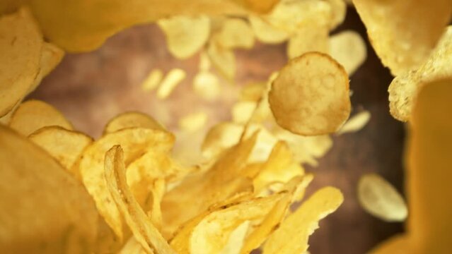 Super Slow Motion Shot of Premium Potato Chips Falling Down on Abstract Brown Background at 1000fps.