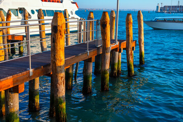 Old pier with wooden pillars in Venice, Italy . Aged waterfront with weathered wooden pilings in...