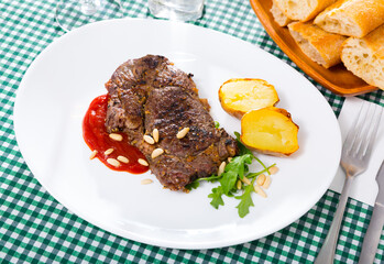 Prepared beef steak with tomatoe ketchup and pine nuts at plate