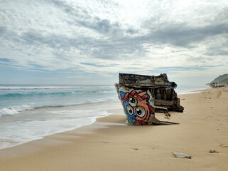 The wreckage of a wooden ship on a sandy beach on the ocean. The shipwreck