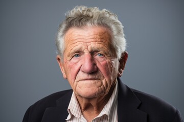 Portrait of senior man with grey hair. Studio shot over grey background.