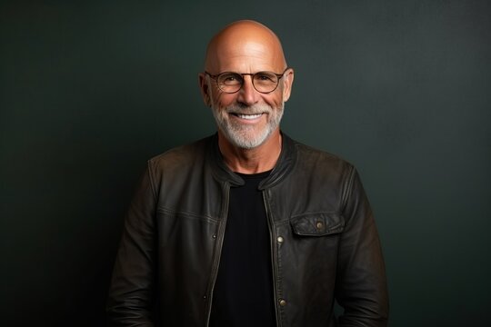 Portrait of a smiling senior man wearing glasses and a leather jacket.