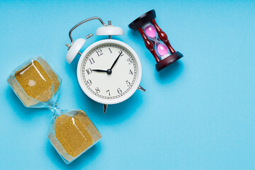 Hourglass and Alarm Clock on Blue Background, Copy Space