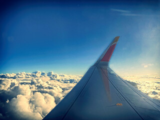 Fototapeta na wymiar Wing of an airplane flying over the clouds