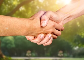 Two people shaking hands on outdoor background