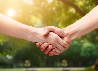 Two people shaking hands on outdoor background