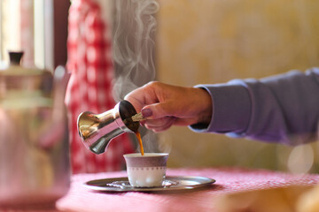 Elderly woman savors the serenity of the morning as she enjoys a cup of coffee on the porch of her rustic cottage, finding solace in the simplicity of nature and contemplative moments