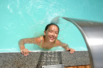 menina criança feliz e sorridente em cascata de piscina 