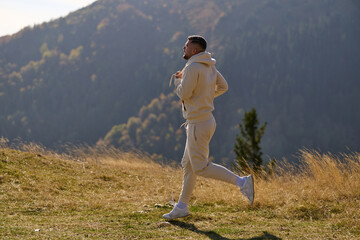 A handsome man maintains his healthy lifestyle as he runs along beautiful natural trails, embodying the essence of fitness, wellness, and vitality in the midst of scenic outdoor surroundings.