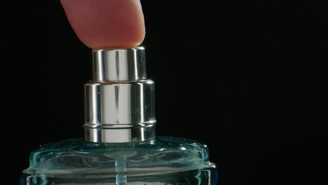 Young man applying perfume to skin in the dark, close up of spraying deodorant luxury perfume.