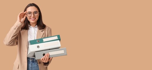 Young businesswoman with document folders on beige background with space for text