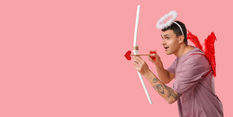 Young man dressed as Cupid with bow on pink background with space for text. Valentine's Day...