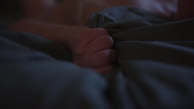 Female Hand Passionately Grabbing Bedsheet While Making Love. closeup shot