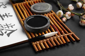 Bamboo mat with ink and brush on dark background, closeup. International Haiku Poetry Day