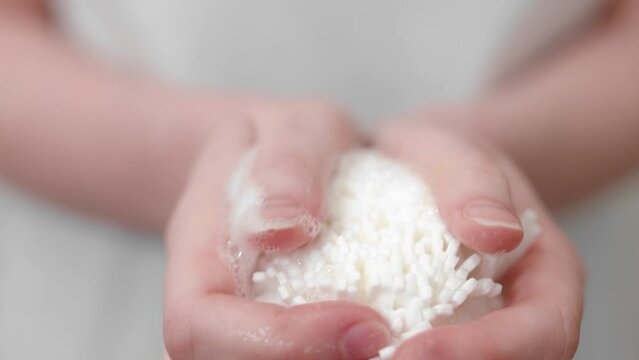 Woman holds white body puff full with soap, body care concept