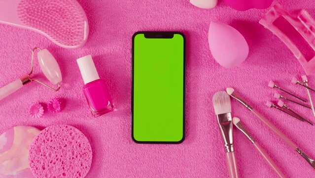 Phone with green screen chroma key among fashion pink women stylish accessories outfit , girl glamour set with label flat lay pastel background table phone, glasses, female clothing offers shopping