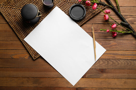 Composition with blank sheet of paper, nib pen and ink on wooden background. International Haiku Poetry Day - Powered by Adobe