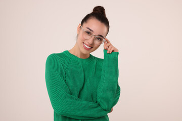 Beautiful young woman in stylish warm sweater on light grey background